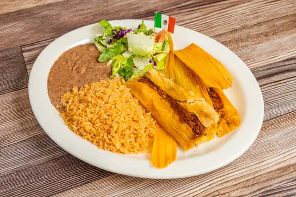 Traditional tamales served with seasoned rice, refried beans, and lettuce