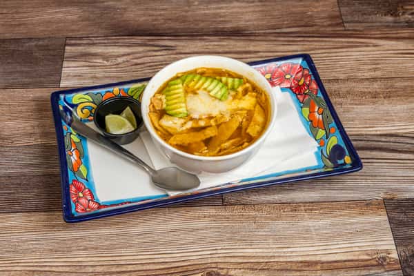 Traditional tortilla soup served with avocado and fresh Mexican-style accompaniments
