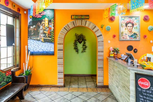 Colorful interior entrance with bright orange walls and decorative Mexican artwork