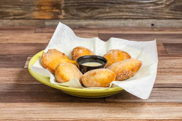 Warm golden pastry bites arranged around a creamy dipping sauce