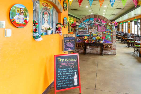 Bright restaurant interior with colorful walls, Mexican artwork, and a specials board