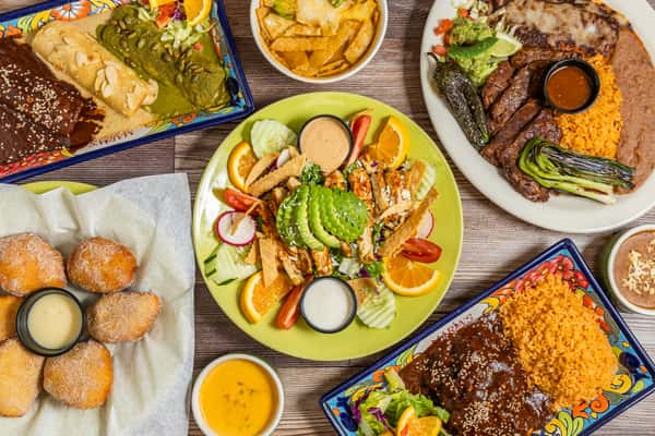 Overhead spread of Mexican dishes including salad, mole, rice, beans, and appetizers