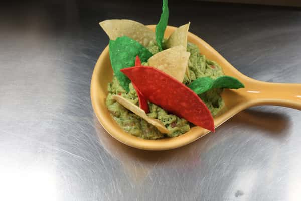 Guacamole served with tortilla chips and a red chile pepper