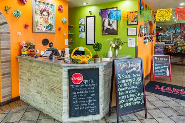 Colorful front counter and host area with menu boards inside Maria's Mexican Grill
