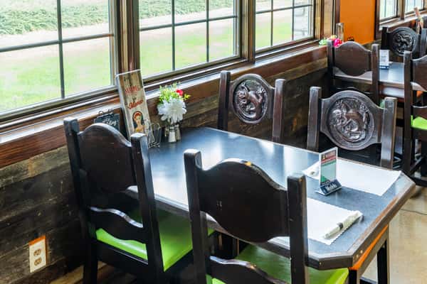 Restaurant seating area beside large windows with tables and colorful chairs