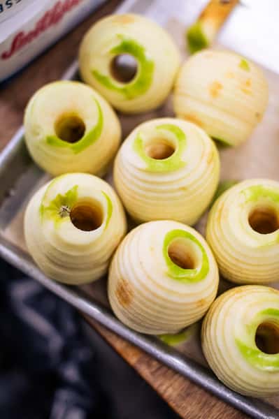 Tray of peeled and cored green apples, neatly arranged and ready for baking or cooking preparation.