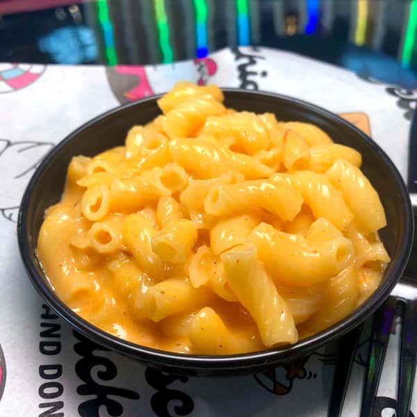 Creamy mac and cheese served in a black bowl, featuring perfectly cooked pasta coated in rich, melted cheddar cheese — a comforting Southern-style side dish from a chicken and donuts restaurant.
