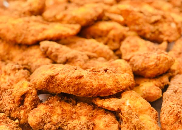 Close-up of a large batch of crispy golden fried chicken tenders, showcasing their crunchy seasoned coating — a mouthwatering Southern comfort food favorite ideal for sharing or catering.