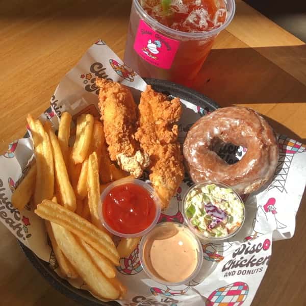 Combo meal of crispy chicken tenders, thick-cut fries, glazed donut, creamy coleslaw, and dipping sauces, served with a refreshing iced drink on branded Disco Chicken and Donuts paper — a bold and playful twist on comfort food classics.