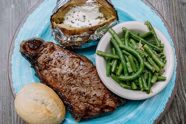 ribeye meal with baked potato, roll and green beans