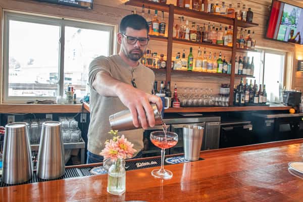bartender preparing cocktails at a lively bar with fresh ingredients and glassware