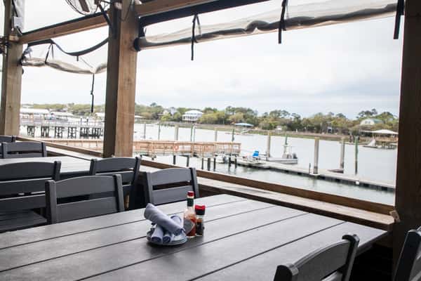 covered waterfront patio dining area with tables overlooking a marina and dock views