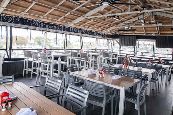 open-air restaurant dining area with wooden tables and chairs under a covered patio