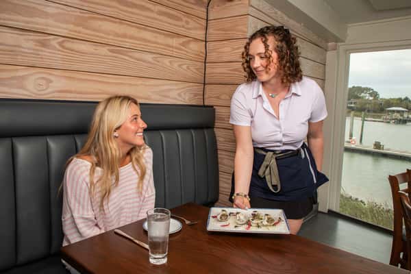 server presenting a plated dish to a guest in a cozy restaurant dining area