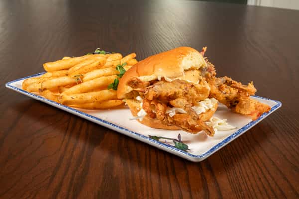 crispy soft shell crab sandwich stacked with toppings on a toasted bun with fries