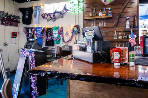 Bar counter decorated with colorful hanging beads and string lights, with a point-of-sale system on a wooden countertop inside a restaurant