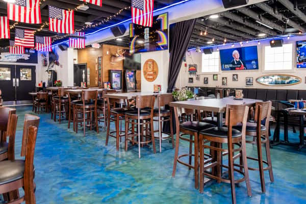 Spacious dining room with high-top seating, coastal-inspired décor, and a lively beach bar atmosphere at Sharky's NSB on Flagler Avenue in New Smyrna Beach.