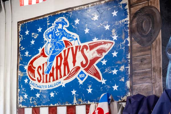 Sharky's logo artwork featuring a pirate shark mascot on a red, white, and blue patriotic background, displayed as wall decor inside a restaurant