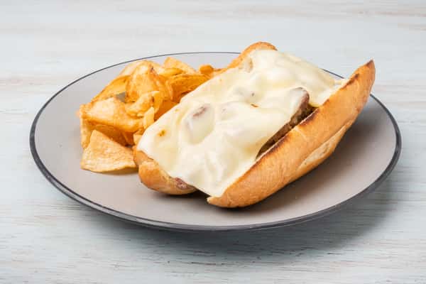Steak tips sandwich topped with melted cheese on a toasted sub roll, served on a gray plate at a restaurant