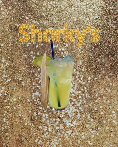 Bright green margarita cocktail with lime garnish in front of a glittery Sharky's backdrop