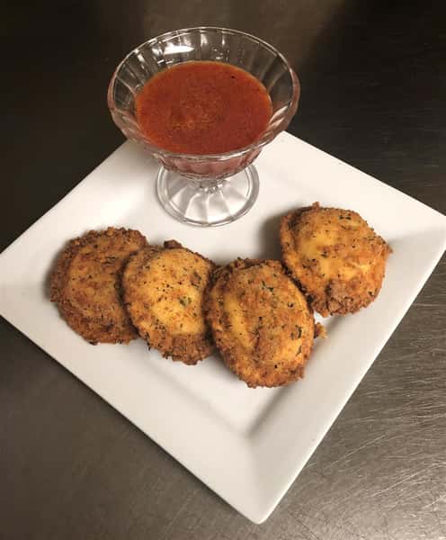 4 fried raviolis on a dish with a side of sauce