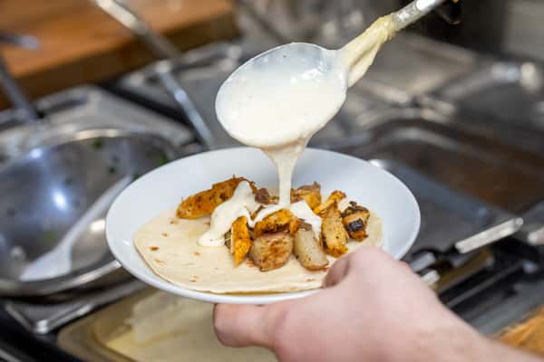 Chef pouring cheese sauce on a taco