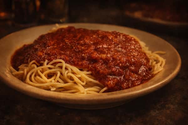 Spaghetti with red tomato sauce, fresh parsley, grated cheese, and two pieces of toasted bread.