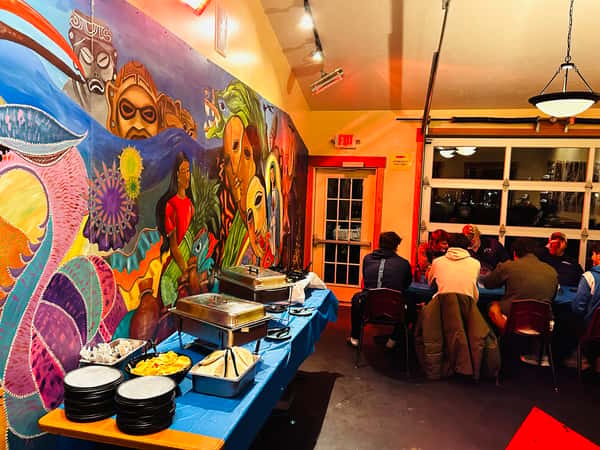 Interior view showing a large colorful mural wall and a buffet style table setup.