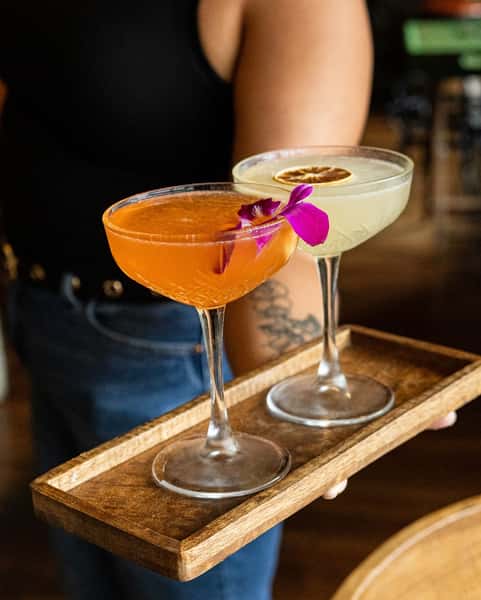 Two specialty cocktails on a tray