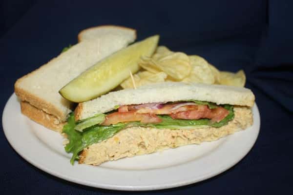 tuna salad sandwich served with chips and a pickle