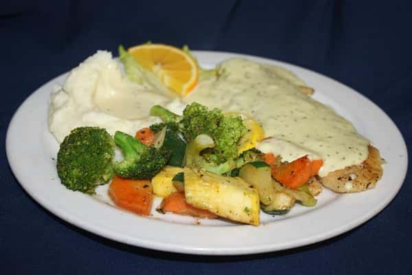 fish with a cream sauce, with a side of masheed potatoes and sauteed vegetables