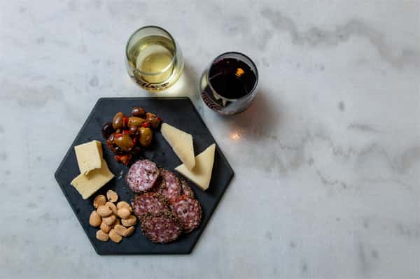 charcuterie items on a dish with two wine glasses