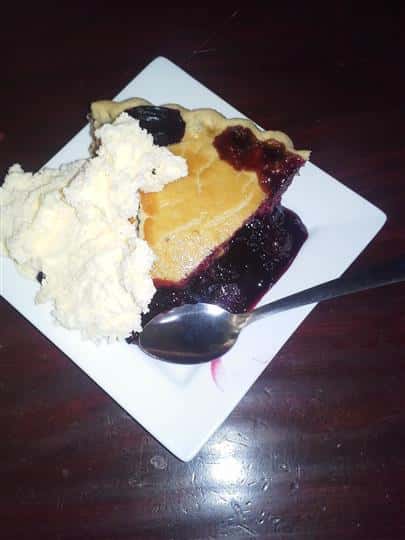 A piece of berrie-pie served with cream cheese