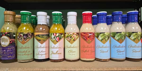 bottled salad dressings and marinades in various flavors lined up on a wooden shelf