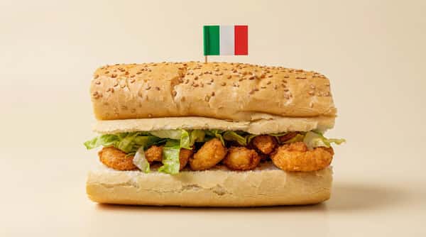 crispy shrimp po boy sandwich with lettuce on a sesame roll and Italian flag pick
