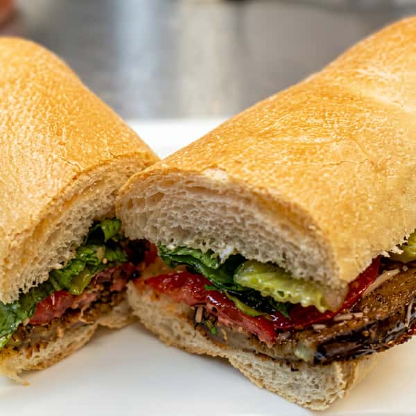 italian hoagie sandwich with sliced meats lettuce tomato and dressing on a crusty sub roll