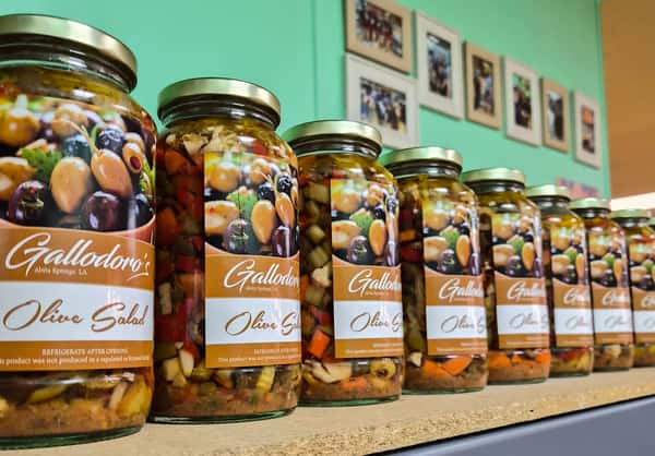mixed olives in marinade displayed in glass jars on a market shelf