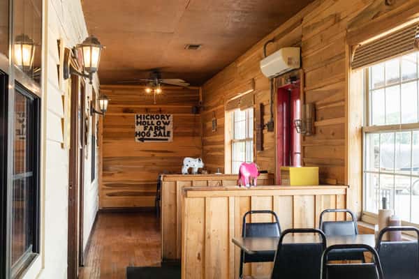 Warm restaurant interior corner featuring wood-paneled walls, a rustic bar counter, and casual seating