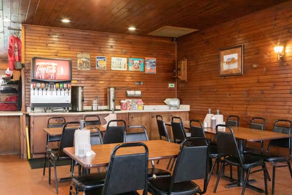 Cozy dining room interior with wood-paneled walls, round tables, and black chairs