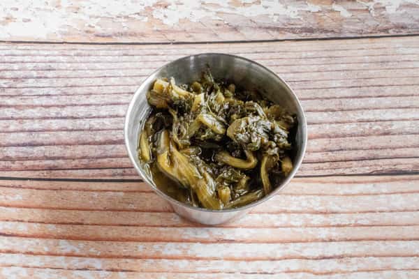 A bowl of slow-cooked Southern turnip greens on a wooden surface