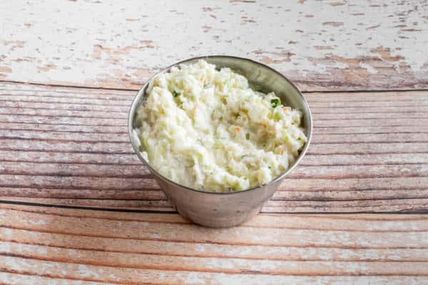 A bowl of creamy homemade coleslaw on a wooden surface
