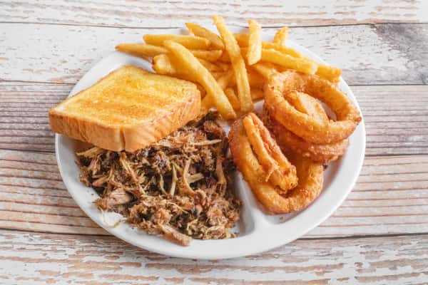A BBQ plate with pulled smoked meat, golden french fries, onion rings, and cornbread on a white plate