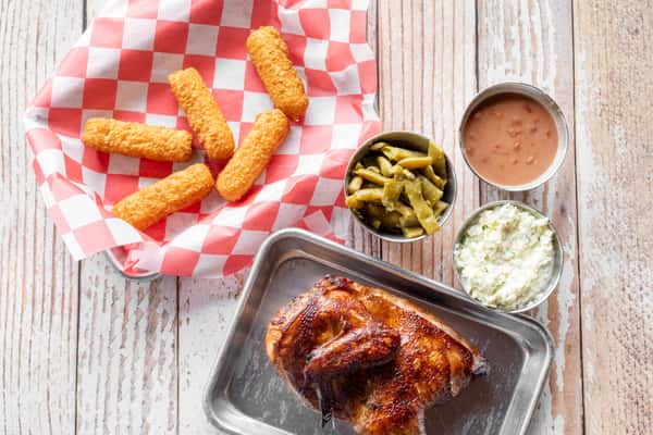 A BBQ spread featuring smoked ribs, golden fries, green beans, and a dipping sauce in a tray