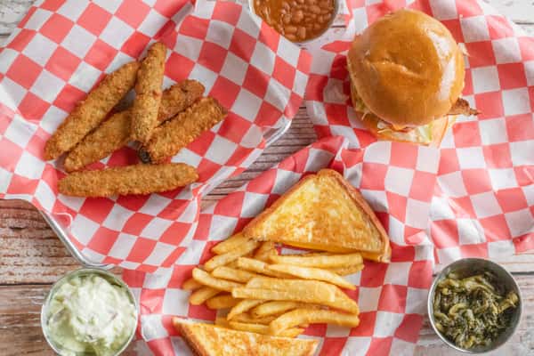 A spread of BBQ food including crispy onion rings, golden french fries, toasted bread, and a side of dipping sauce served on red and white checkered paper