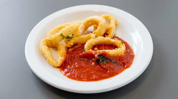 Fried calamari rings on a white plate with a red marinara sauce, garnished with parsley.