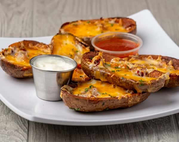 Potato skins topped with melted orange and white cheeses, served with a side of sour cream and red sauce.