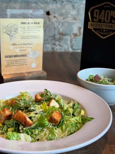 Classic Caesar salad topped with shredded parmesan and crunchy croutons served in a white bowl on a rustic wood table.