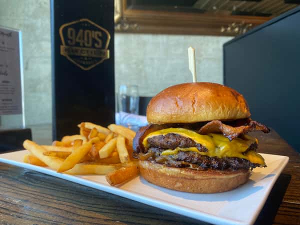 Juicy double bacon cheeseburger served with crispy fries on a white plate — a hearty and classic American meal.