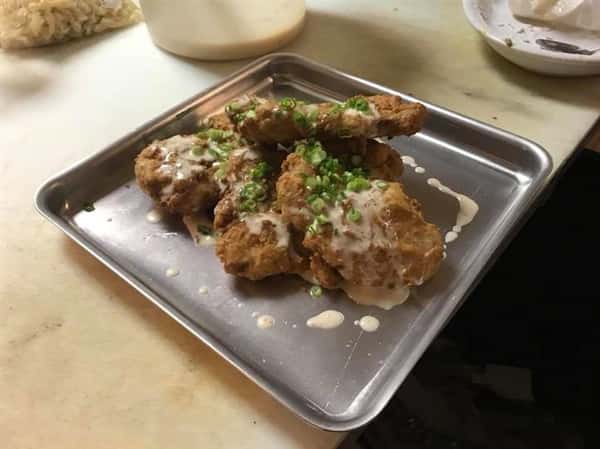 Fried chicken bites drizzled with sauce and sprinkled with green onion
