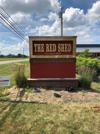 Road sign of the restaurant right by the street that writes "The Red Shed"